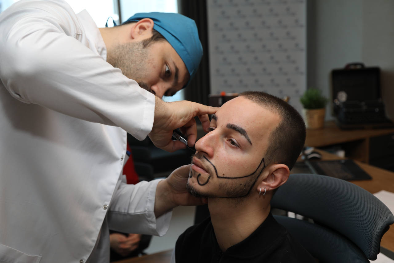 le dr balwi examine un patient souffrant d´une la pelade de barbe