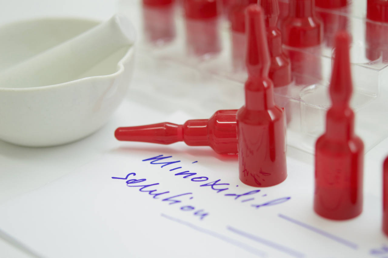 gros plan sur des flacons et une feuille sur laquelle est inscrite une prescription de solution de minoxidil pour cheveux