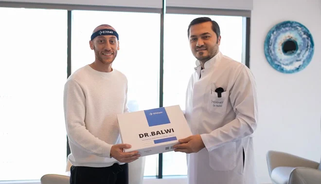 Photo qui montre le Dr Balwi donnant un kit Hair Boost d'Elithair à un patient.