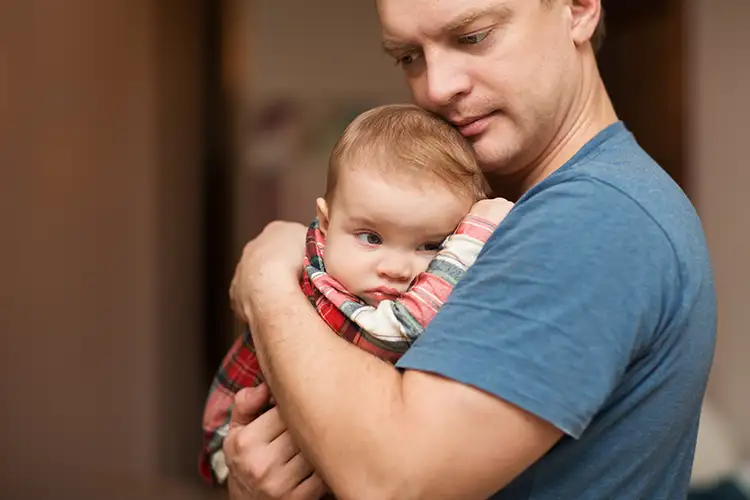 père tenant son fils dans les bras inquiet de son avenir génétique à transmettre à son fils