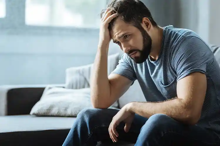 homme deprime avec une main sur la tete triste