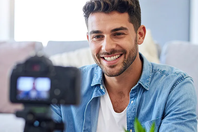 Un jeune homme souriant se trouve devant la caméra pendant un tournage, concentré sur la création de contenu vidéo dynamique.