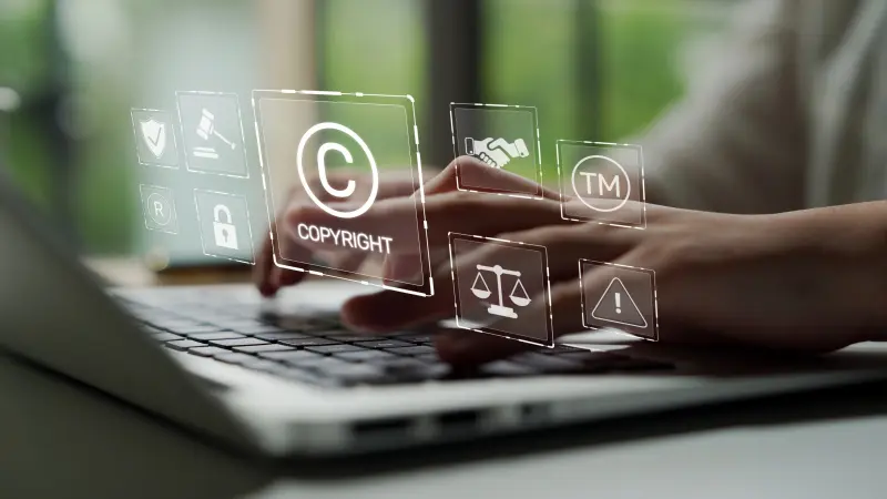 Une personne tape sur un ordinateur portable avec des symboles juridiques en surimpression