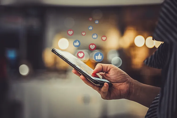 Un téléphone portable affiche des notifications de mentions « j’aime » sur les réseaux sociaux, symbole d’interaction et de reconnaissance en ligne.