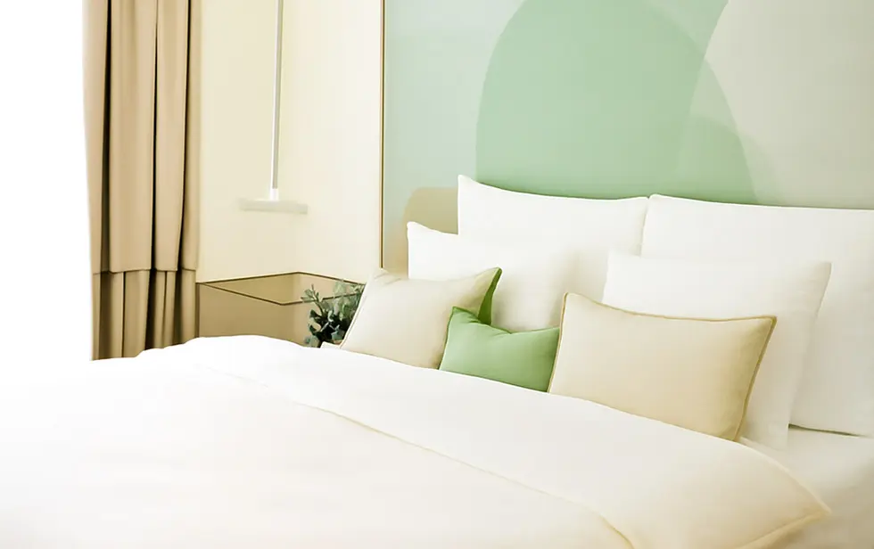 Détail lumineux d’une chambre de l’Elitoria Hotel avec literie et touches de vert