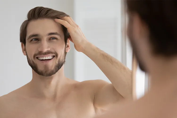 Homme souriant passant la main dans ses cheveux avec une expression de bien être et de confiance