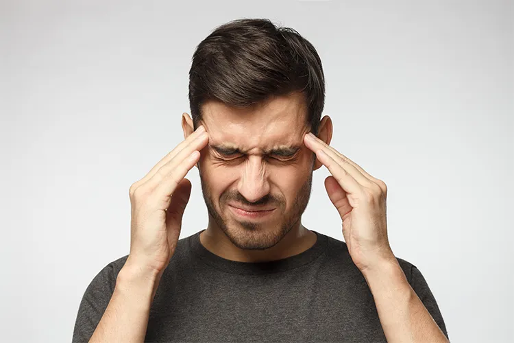 Homme exprimant une tension intense en tenant sa tête avec les mains sous l’effet du stress