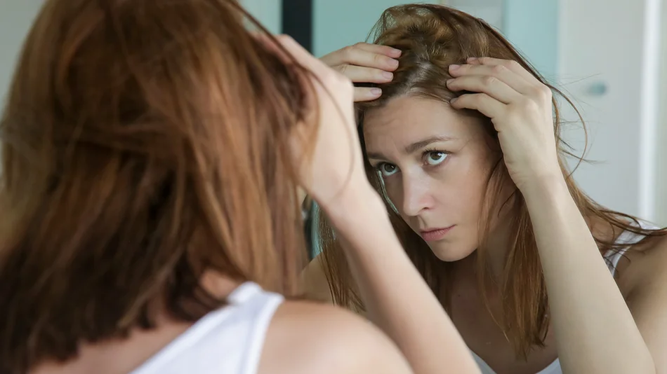 Femme observant sa ligne capillaire dans un miroir pour vérifier la perte de cheveux